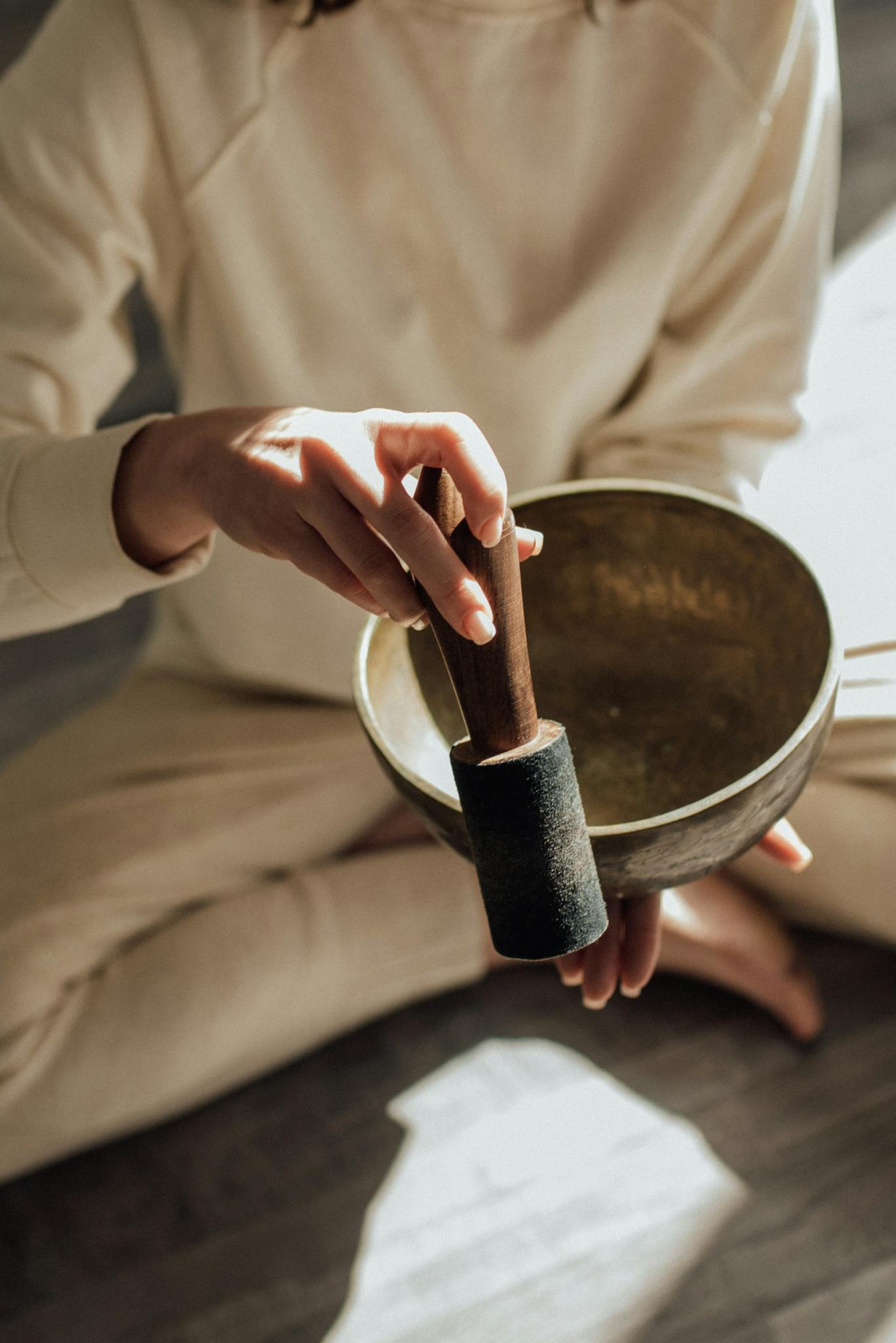 A person holds a Tibetan singing bowl with a mallet, symbolizing meditation and relaxation.